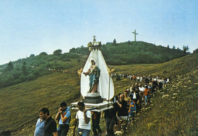 La statua de Maria Ausiliatrice portà in procession, che torna al Santuario; sul sfondo la Crose.